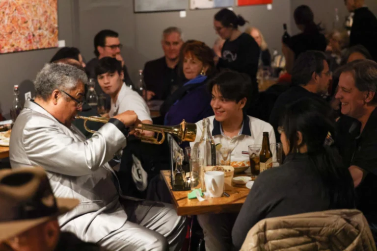Jon Faddis playing the trumpet at a fan's table at the Jazz Forum club